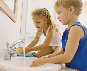 Young girl and boy washing their hands in a bathroom sink