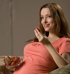 Pregnant woman eating strawberries..