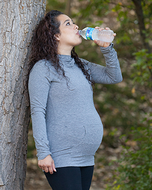 Pregnant woman drinking bottled water.