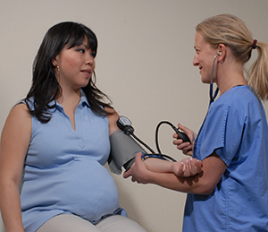 Healthcare provider taking pregnant woman's blood pressure
