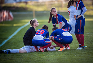 Group of female soccer players and referee gathered around an injured player