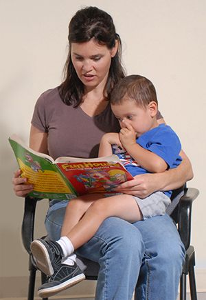 Woman holding boy on lap, reading to him.
